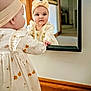 baby, child, girl, mirror, reflection, headband, dress, curious, indoor, carpet, wooden_trim, wall, hand, face, portrait, clothing, home, soft_light, cute, infant