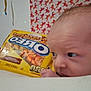 Blake is registered to the contest to win money with this photo: baby, infant, face, head, oreo, cookie_package, snack, yellow, curious, looking, closeup, child, indoor, person, patterned_wall, hand, light, soft_focus, food, package