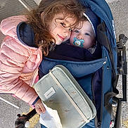 Naël participe au concours pour gagner de l'argent avec cette photo : baby, baby_carriage, blue_eyes, casual, child, curly_hair, cute, family, holding, jacket, love, outdoor, pacifier, person, pouch, smile, stroller, tissue, urban, winter_clothing