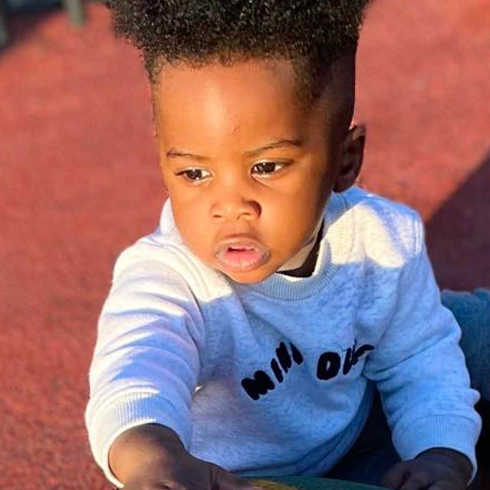 Grâce Miguel participe au concours pour gagner de l'argent avec cette photo : activity, casual_clothing, child, colorful, curiosity, curly_hair, daylight, expression, face, hand, outdoor, person, playground, portrait, skin, sunlight, sweater, texture, toddler, young