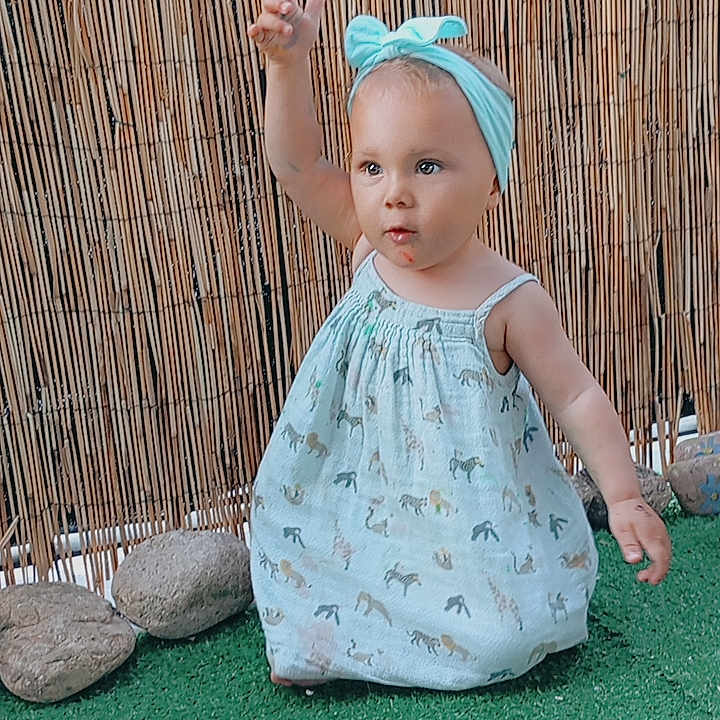 Lèvanah participe au concours pour gagner de l'argent avec cette photo : accessories, baby, bodypart, cap, clothing, dress, eveningdress, face, fashion, finger, grass, hand, hat, head, person, photography, plant, portrait, sitting, wood