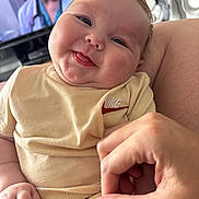 Teddy joined the competition — help win amazing prizes! baby, child, smiling, tongue_out, hand, fingers, clothing, beige, person, face, indoor, television, blurred_background, cute, infant, portrait, closeup, skin, expression, holding_hand