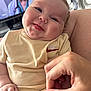 baby, child, smiling, tongue_out, hand, fingers, clothing, beige, person, face, indoor, television, blurred_background, cute, infant, portrait, closeup, skin, expression, holding_hand