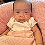 Nora is registered to the contest to win money with this photo: baby, infant, pink_blanket, white_onesie, face, eyes, arm, hand, pillow, indoors, soft_texture, head, skin, newborn, person, portrait, seated, comfortable, resting, cute