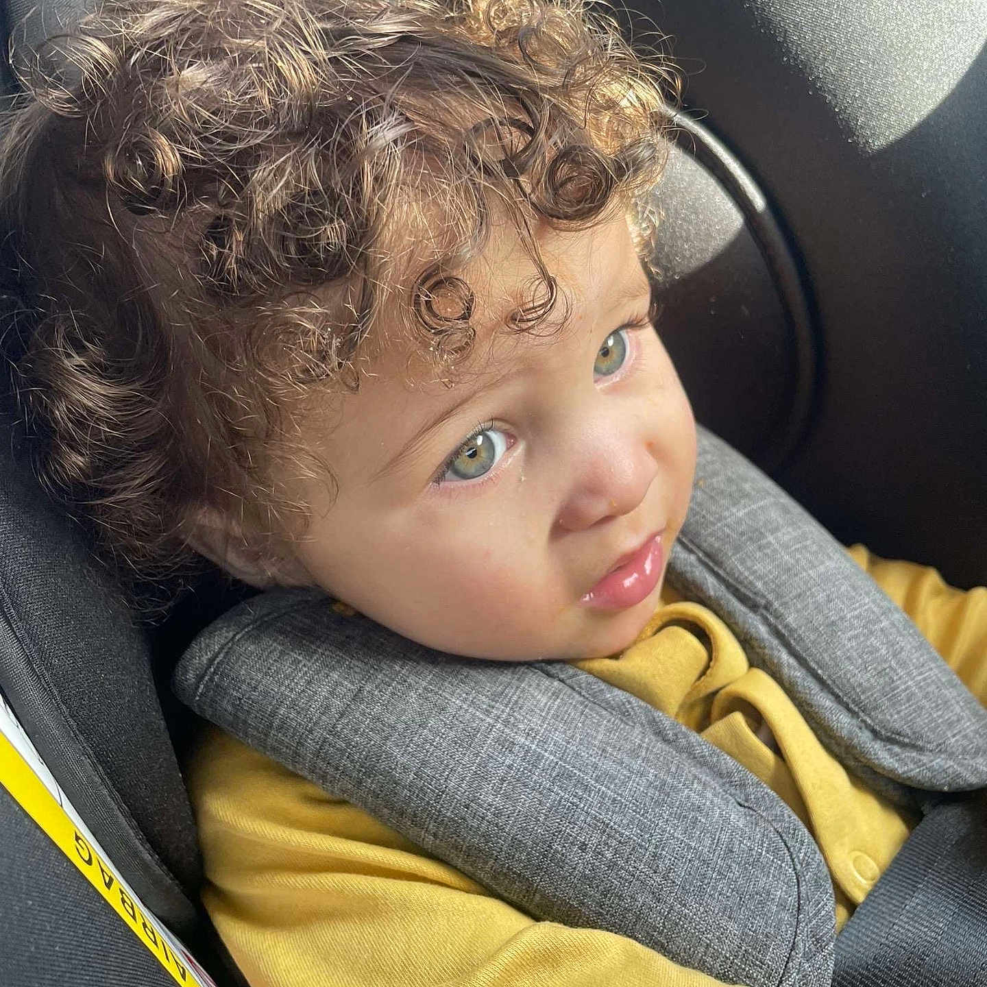 Xyondre joined the competition — help win amazing prizes! baby, car_seat, child, closeup, curly_hair, cute, expression, face, green_eyes, head, indoors, infant, portrait, safety, seat, seatbelt, sunlight, toddler, yellow_clothing, young_child