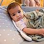 Neveah is registered to the contest to win money with this photo: baby, infant, blanket, cushion, polka_dot, face, child, soft_texture, indoor, seat, relaxing, looking, young, cute, comfort, clothing, person, head, expression, resting
