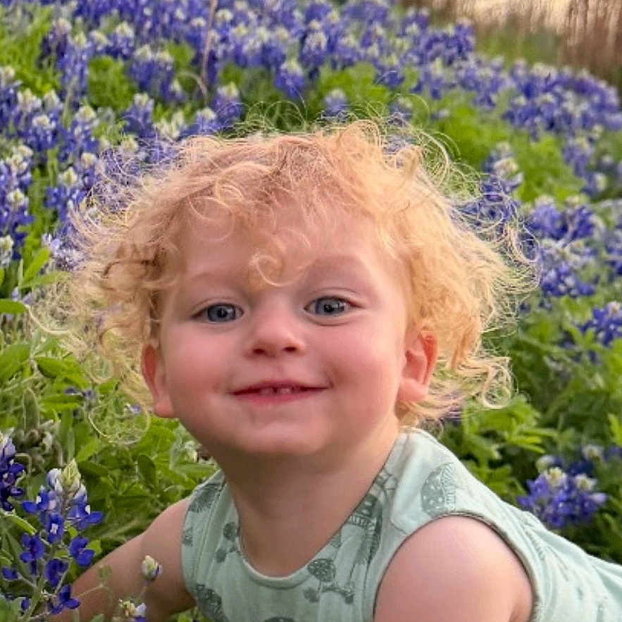 Harrison joined the competition — help win amazing prizes! child, toddler, curly_hair, smiling, bluebonnets, flowers, nature, outdoor, grass, greenery, pond, trees, sunset, happy, cute, baby, plants, spring, crawling, portrait