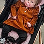 baby, black_pants, child, clothing, comfort, cushion, cute, dress, face, floor, footwear, indoor, infant, pacifier, person, pink_pillow, seated, sneakers, star_pattern, stroller