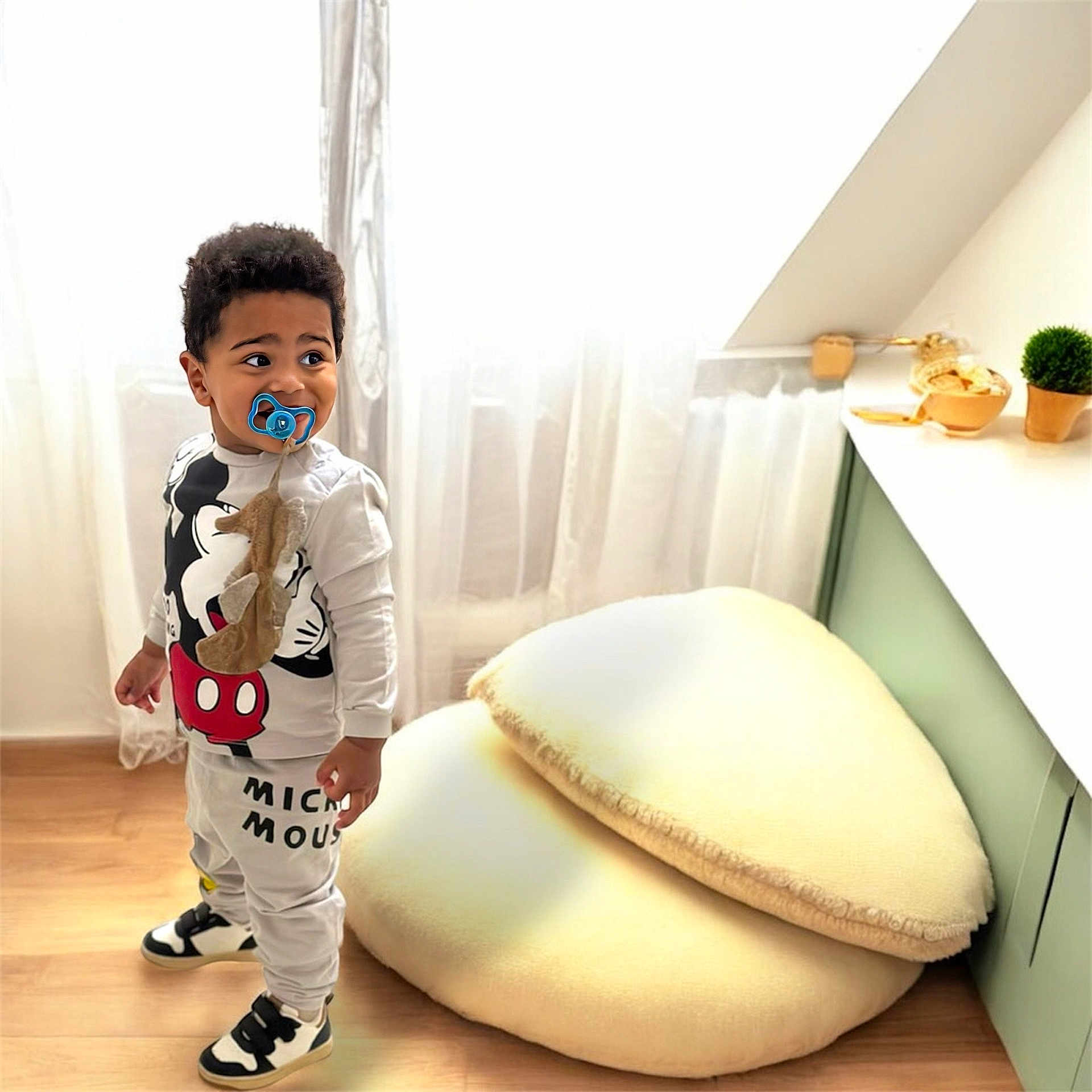 Tyler a rejoint le concours — aidez-le/la à gagner de superbes lots ! cabinet, child, clothing, curtains, cushions, decor, expression, floor, furniture, indoor, mickey_mouse, pacifier, plant, room, sneakers, soft_lighting, standing, toddler, window, young_child