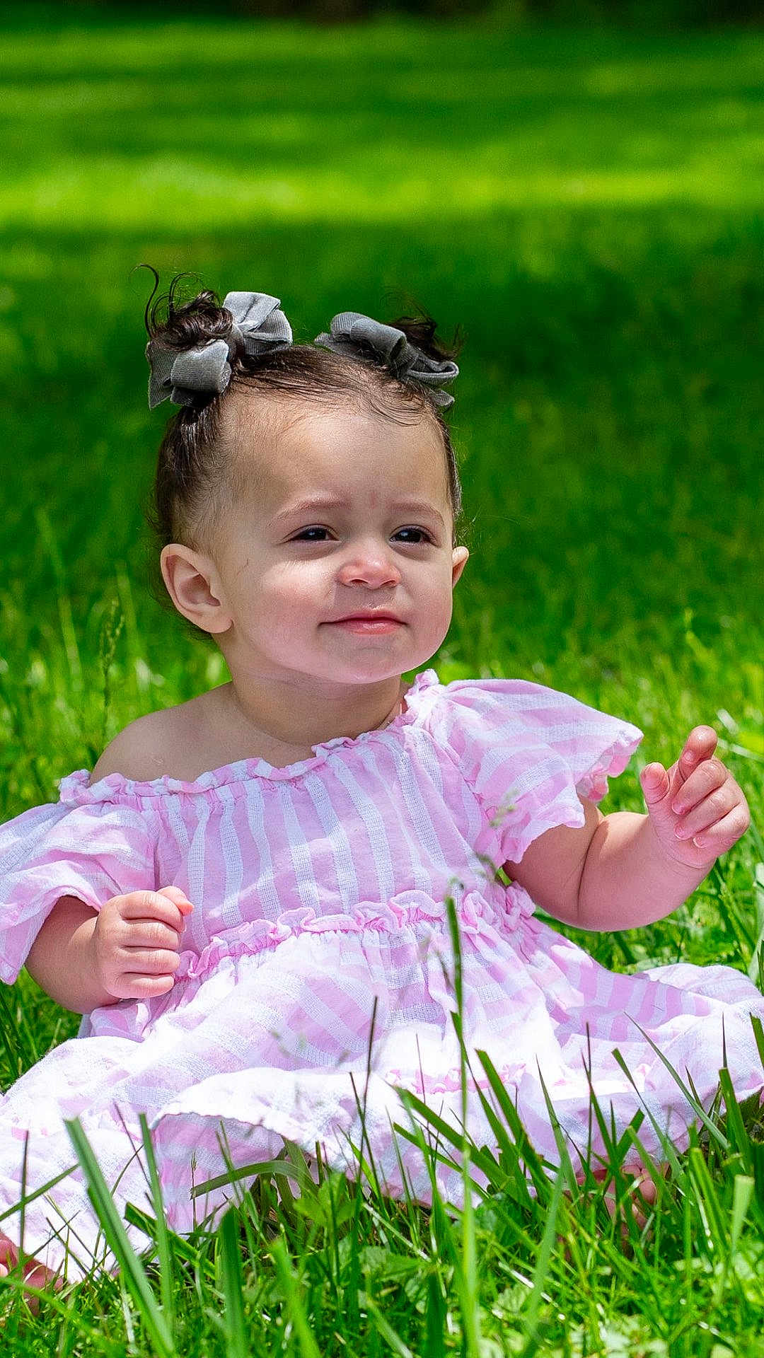 Nevaeh joined the competition — help win amazing prizes! toddler, child, grass, outdoor, dress, pink, striped, pigtails, hair_bows, sunlight, greenery, cute, baby, sitting, nature, portrait, smile, happy, young, person