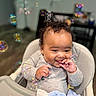 baby, high_chair, smile, curly_hair, indoor, bubbles, playful, child, cozy, happy, seated, clothing, blanket, hand, face, expression, person, cute, infant, table