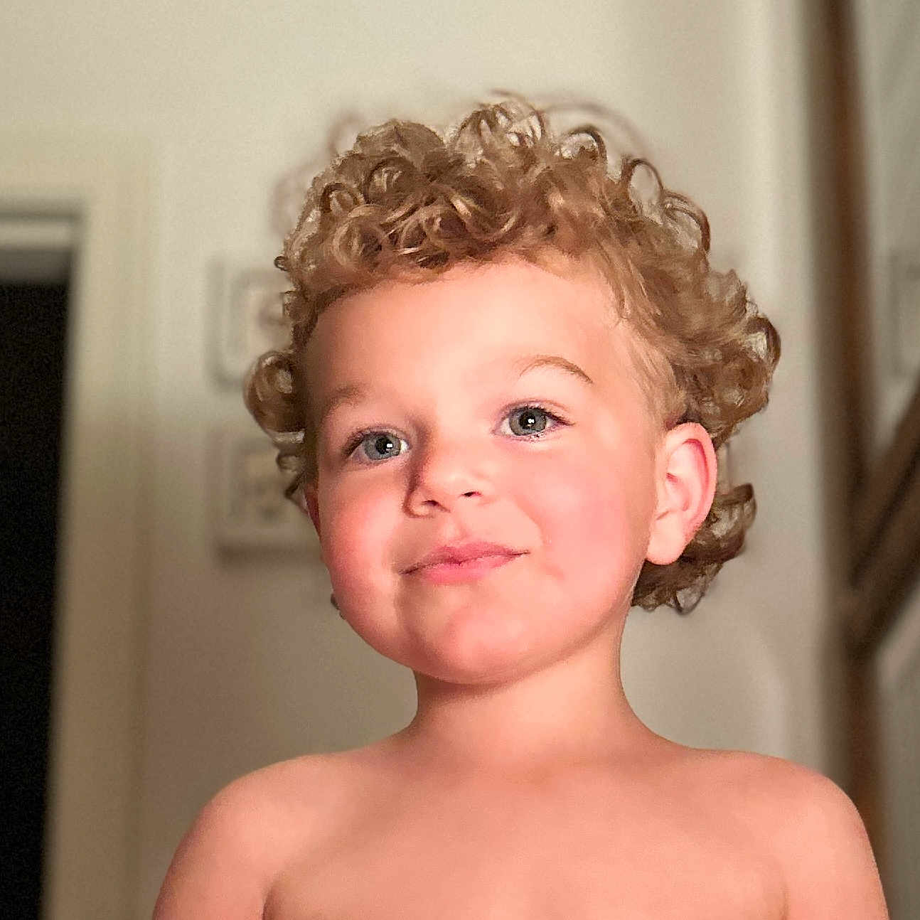 Elston is registered to the contest to win money with this photo: background, bare_shoulders, blond, child, curly_hair, cute, expression, face, happy, head, indoor, innocence, light, person, portrait, room, skin, smiling, toddler, young