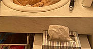 Simba is registered to the contest to win money with this photo: bathroom, cat, cleaning_supplies, countertop, curious, decorative_bird_figurine, domestic_animal, faucet, hairbrush, indoor, orange_cat, personal_care, pet, plastic_drawer, relaxed, resting, sink, tile_floor, tissue_box, toiletries