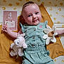Roxane a rejoint le concours — aidez-le/la à gagner de superbes lots ! baby, infant, smiling, plush_toy, flower_toy, milestone_card, green_romper, blanket, yellow_blanket, patterned_wall, cheerful, cute, indoor, child, four_months, happy, portrait, baby_girl, soft_toys, lying_down