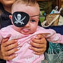 baby, child, eye_patch, pirate, pink_sweatshirt, barbie, tongue_out, smiling_person, braces, hands, holding, indoor, person, cute, playful, face, clothing, portrait, fun, expression