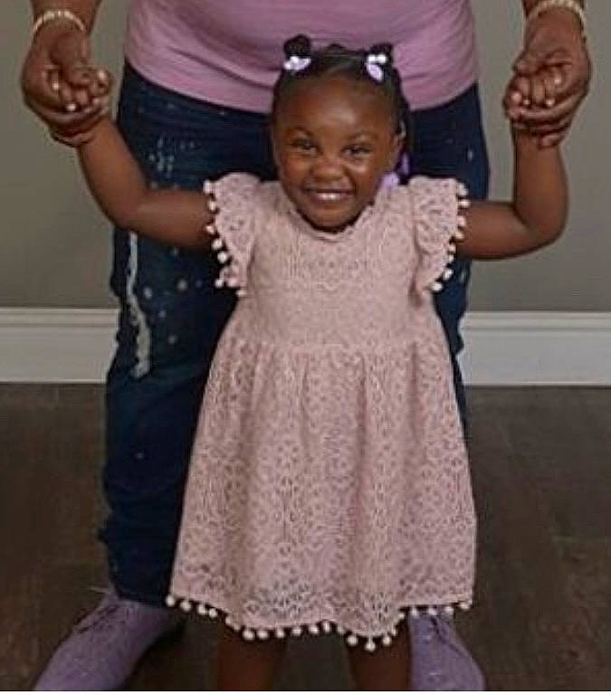 Denver is registered to the contest to win money with this photo: arm, baby_toddler_clothing, child, day_dress, embellishment, event, fashion_accessory, finger, formal_wear, fun, gesture, happy, jewellery, joy, one_piece_garment, person, pink, sleeve, smile, standing