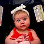 baby, infant, child, bottle, headband, red_dress, car_seat, warning_label, blue_eyes, hands, face, cute, indoors, person, sitting, feeding, closeup, expression, portrait, young