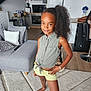 Awa a rejoint le concours — aidez-le/la à gagner de superbes lots ! child, girl, posing, curly_hair, living_room, sofa, cushion, carpet, barefoot, shorts, sleeveless_shirt, modern_kitchen, wood_floor, bracelet, home_interior, smiling, person, furniture, plant, decor