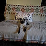 cat, kitten, siamese_cat, pet, animal, sitting, bed, bedspread, pillow, cushion, patterned_fabric, indoor, home, cozy, portrait, blue_eyes, dark_face, white_fur, black_paws, photography