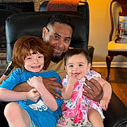 Rya joined the competition — help win amazing prizes! child, baby, man, smiling, happy, family, indoor, living_room, chair, lamp, furniture, red_hair, floral_dress, casual_clothing, hug, portrait, people, wood_floor, home_decor, candid