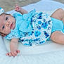 Ember is registered to the contest to win money with this photo: baby, infant, blue_clothing, headband, bow, floral_pattern, cushion, lying_down, cute, portrait, child, soft_texture, skin, eyes, baby_girl, young_child, indoors, comfort, relaxing, small_hands
