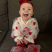 Aurora Jaide joined the competition — help win amazing prizes! baby, child, clothing, couch, cute, drool, hands, happy, headband, hearts, indoor, infant, mouth_open, onesie, portrait, red_bow, sitting, smile, sofa, toes