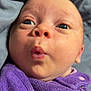 baby, infant, face, eyes, mouth, purple_clothing, fabric, close_up, skin, expression, newborn, cute, soft_texture, portrait, person, child, lying_down, indoors, head, warm_clothing