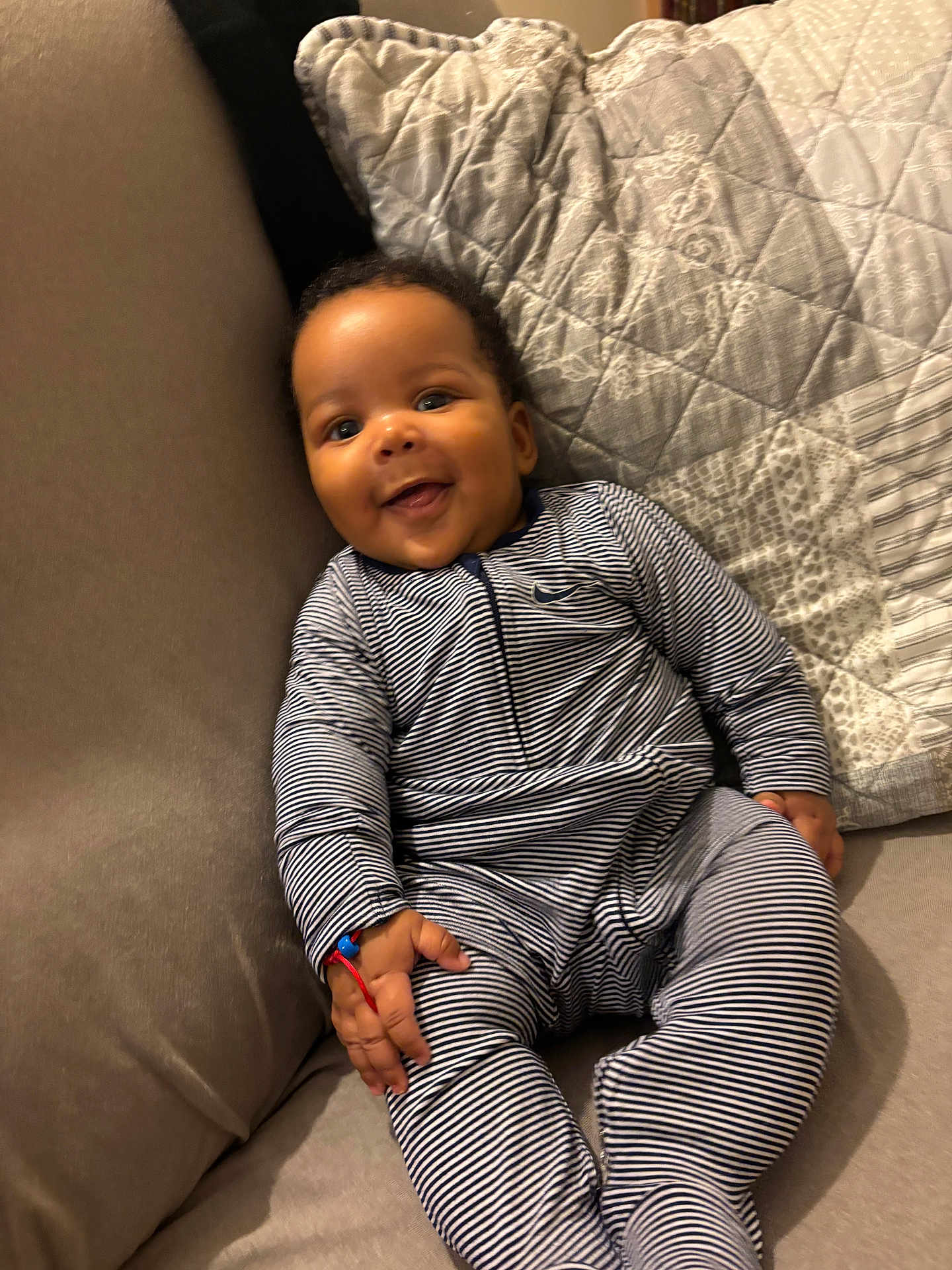 Jahleel participe au concours pour gagner de l'argent avec cette photo : baby, child, smile, striped_clothing, couch, quilt, indoor, happy, infant, person, seated, cozy, cute, home, furniture, soft, relaxed, portrait, one_person, casual