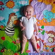 Lily is registered to the contest to win money with this photo: baby, child, smiling, onesie, playmat, cartoon_animals, elephant, zebra, monkey, sun, bird, green, purple, orange, blue, happy, infant, colorful, cute, toy