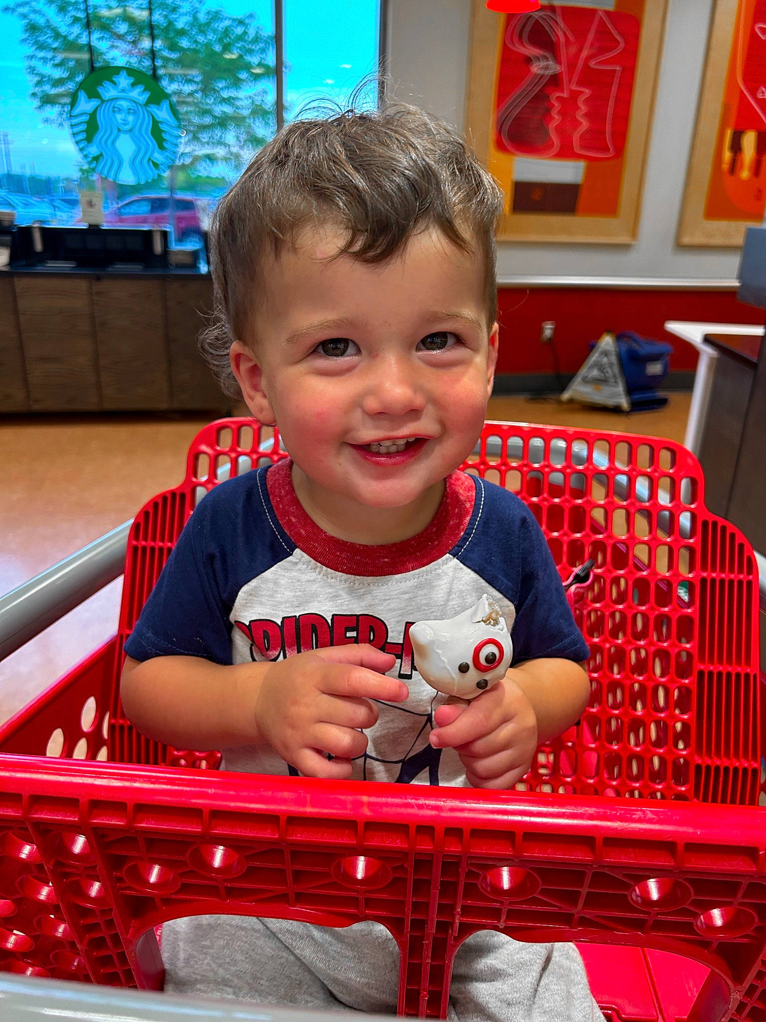 Kash is registered to the contest to win money with this photo: baby, child, event, facial_expression, fun, happy, houseplant, joy, leisure, motor_vehicle, pattern, person, picture_frame, recreation, red, shopping_cart, sitting, smile, standing, t_shirt