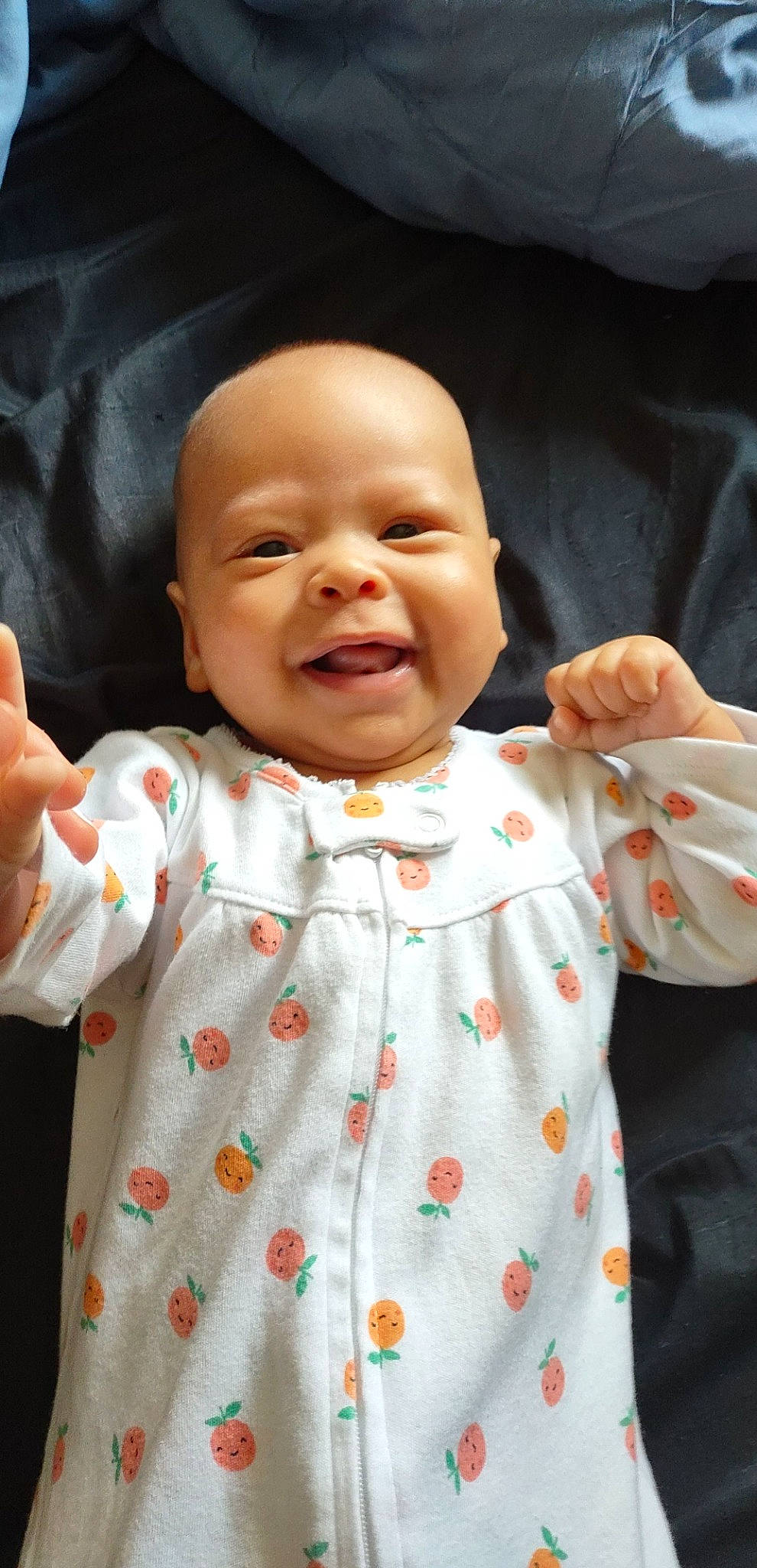 Emberlee is registered to the contest to win money with this photo: arm, baby, baby_toddler_clothing, cheek, chin, face, facial_expression, gesture, hand, head, lip, mouth, nose, orange, person, product, skin, sleeve, smile, standing