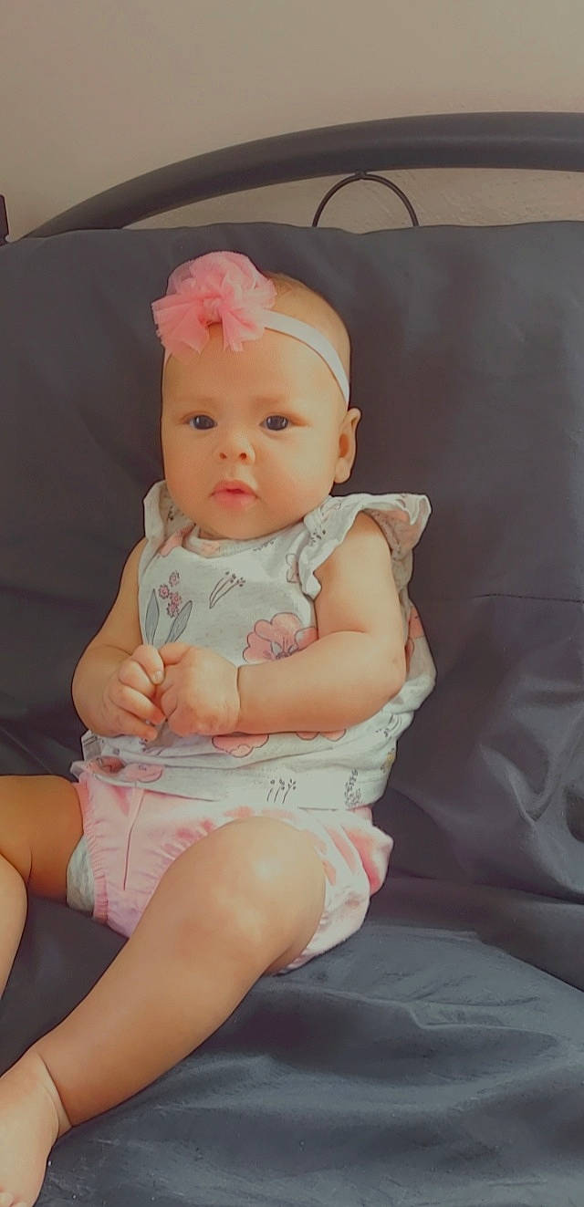 Emberlee is registered to the contest to win money with this photo: baby, baby_toddler_clothing, blond, chair, cheek, child, comfort, dress, flash_photography, headband, headwear, human_leg, iris, jewellery, lip, person, pink, skin, sleeve, textile