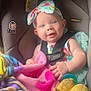 baby, child, car_seat, seat_belt, headband, blanket, toy, plush_toy, smiling, blue_eyes, infant, colorful_clothing, indoor, safe, cute, happy, toddler, soft_toys, child_safety, portrait
