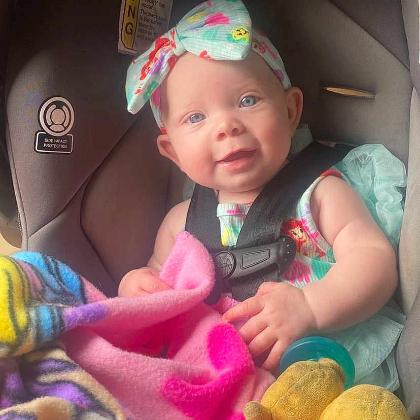 Delilah joined the competition — help win amazing prizes! baby, blanket, blue_eyes, car_seat, child, child_safety, colorful_clothing, cute, happy, headband, indoor, infant, plush_toy, portrait, safe, seat_belt, smiling, soft_toys, toddler, toy