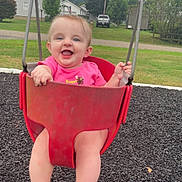 Rosalie joined the competition — help win amazing prizes! baby, child, swing, playground, red_swing, pink_shirt, smiling, happy, outdoor, grass, trees, houses, residential_area, feet, legs, summer, daytime, fun, park, person