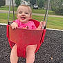 baby, child, swing, playground, red_swing, pink_shirt, smiling, happy, outdoor, grass, trees, houses, residential_area, feet, legs, summer, daytime, fun, park, person