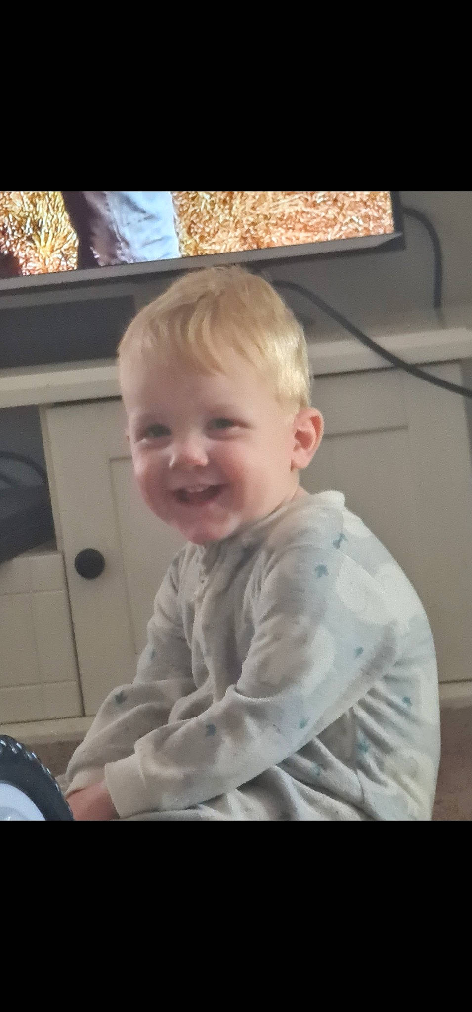 Toby is registered to the contest to win money with this photo: baby, baby_toddler_clothing, blond, cheek, child, chin, cool, eye, flooring, fun, happy, joy, nose, person, play, room, sitting, sleeve, smile, t_shirt