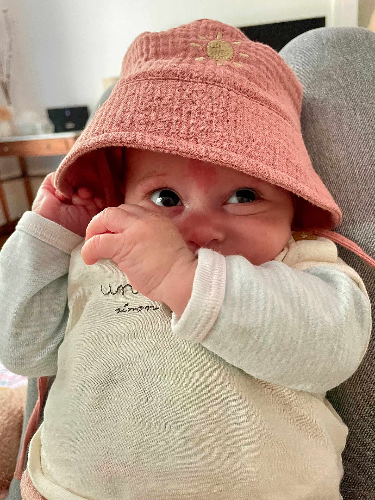 Ellie participe au concours pour gagner de l'argent avec cette photo : baby, infant, hat, pink_hat, clothing, face, hand, indoor, cute, expression, portrait, child, young_child, cozy, sleeves, fabric, person, soft_light, background, closeup