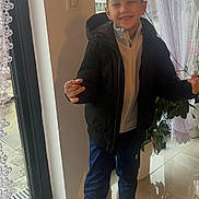 Alessandro a rejoint le concours — aidez-le/la à gagner de superbes lots ! child, boy, smiling, indoor, window, curtains, black_jacket, white_zipper, blue_pants, sneakers, potted_plant, tiled_floor, hand_gesture, happy, portrait, casual_clothing, daylight, reflection, home_interior, standing