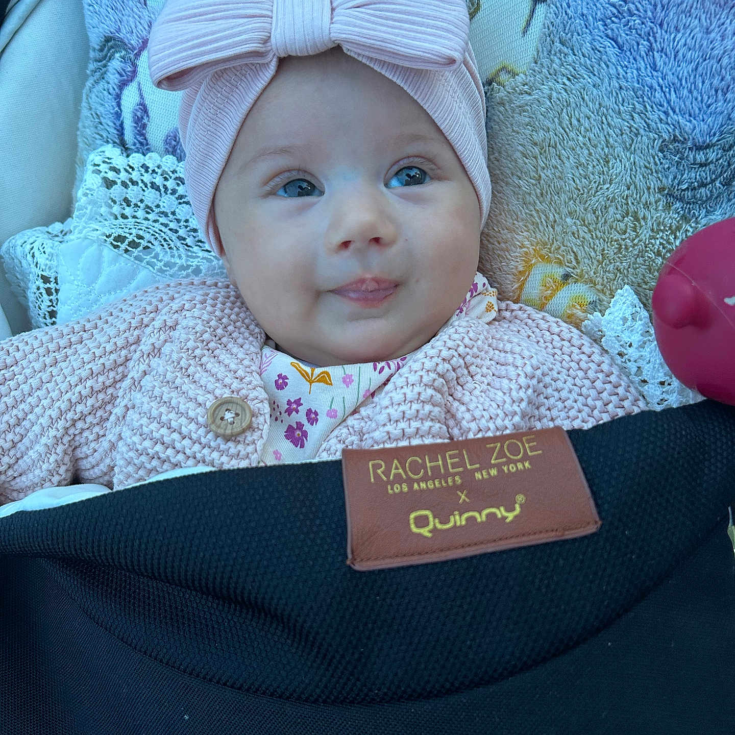 Véronique participe au concours pour gagner de l'argent avec cette photo : baby, headband, bow, pink, knitted_sweater, stroller, blanket, face, infant, cute, portrait, child, soft_texture, cozy, clothing, person, smile, indoors, closeup, toddler