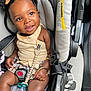 baby, child, car_seat, smiling, pigtails, bows, pacifier, safety_buckle, clothing, seatbelt, infant, happy, cute, portrait, indoor, person, closeup, accessory, warning_label, seat