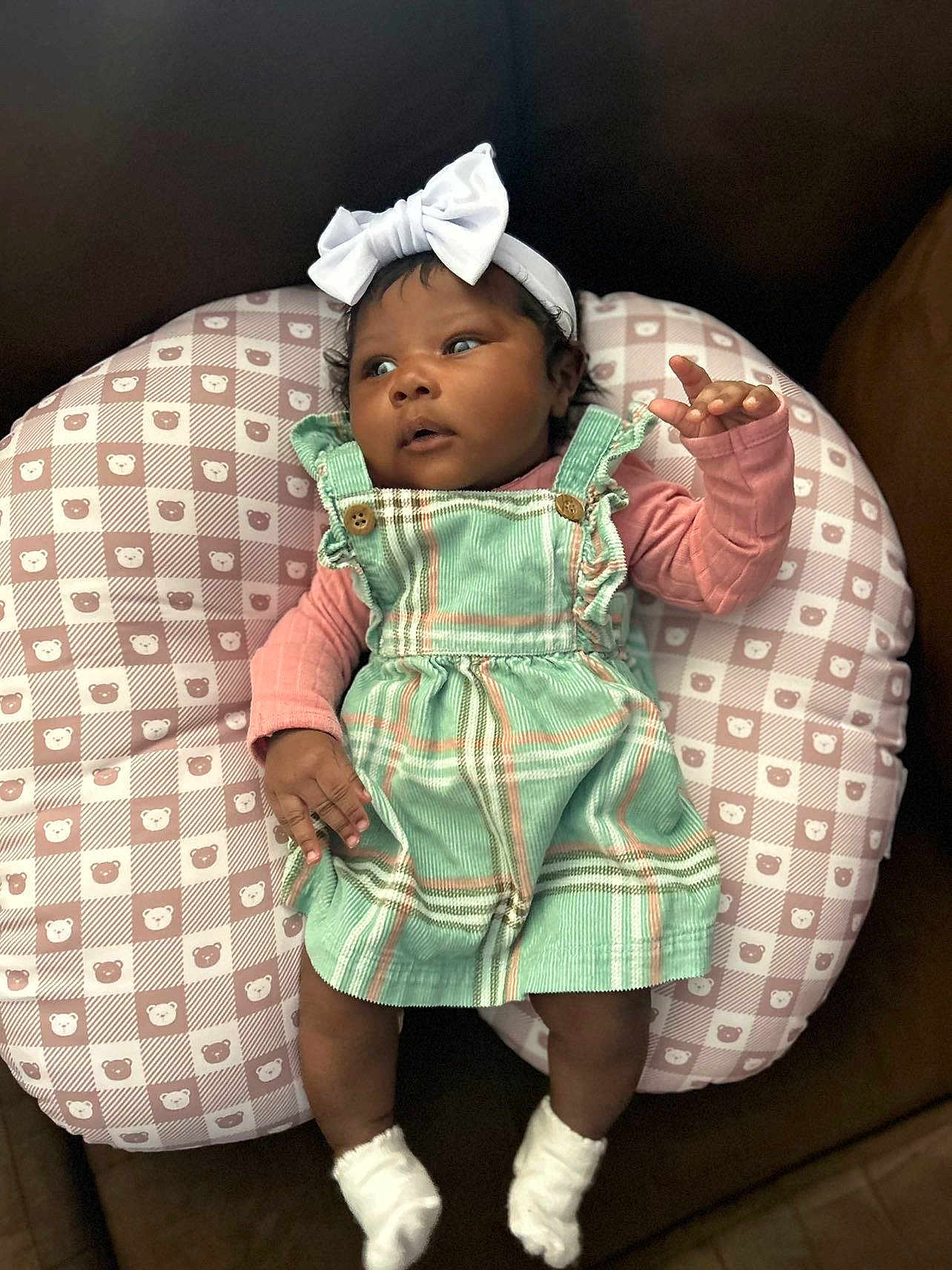 Kehlani joined the competition — help win amazing prizes! baby, infant, headband, bow, cushion, plaid_dress, pink_shirt, white_socks, face, hands, legs, pattern, bear_pattern, indoor, cute, child, portrait, seated, clothing, soft_lighting
