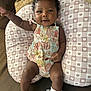 baby, infant, smiling, curly_hair, pillow, bear_pattern, romper, floral, sock, frilly, arm_raised, happy, cute, lying_down, indoors, cozy, child, person, skin, closeup