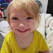 Auralia joined the competition — help win amazing prizes! child, toddler, smiling, yellow_shirt, blonde_hair, face, indoor, blanket, living_room, television, furniture, happy, person, casual, cute, portrait, sitting, cozy, home, young_child
