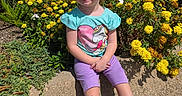 Auralia joined the competition — help win amazing prizes! child, girl, smile, flowers, yellow_flowers, greenery, outdoor, sunny, concrete, sitting, purple_shorts, turquoise_shirt, unicorn, happy, plants, nature, casual_clothing, shoes, blue_socks, daytime