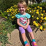 child, girl, smile, flowers, yellow_flowers, greenery, outdoor, sunny, concrete, sitting, purple_shorts, turquoise_shirt, unicorn, happy, plants, nature, casual_clothing, shoes, blue_socks, daytime