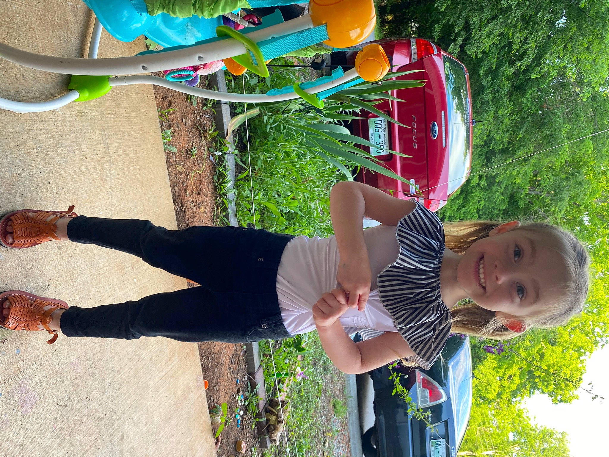 Sara is registered to the contest to win money with this photo: car, child, fun, grass, green, happy, joy, leisure, people_in_nature, person, plant, recreation, red, smile, summer, t_shirt, toddler, tree, vehicle, walking_shoe