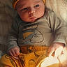 baby, infant, hat, yellow_clothing, cartoon_print, blanket, soft_texture, cozy, sleepwear, child, cute, portrait, indoors, warm_light, resting, newborn, hand, face, expression, comfortable