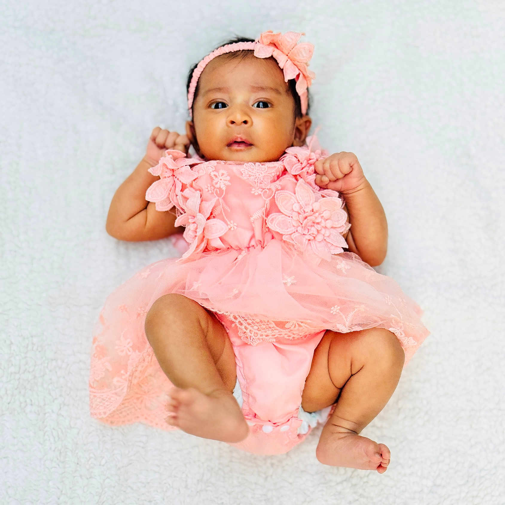 Yazhvi is registered to the contest to win money with this photo: adorable, baby, blanket, child, clothing, cute, expression, fingers, headband, indoor, infant, lace, lying_down, newborn, person, pink_dress, portrait, skin, soft_texture, toes