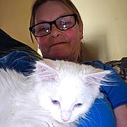 Lucy is registered to the contest to win money with this photo: person, glasses, cat, white_cat, indoor, blue_shirt, pet, relaxed, closeup, feline, cozy, couch, home, comfortable, animal, portrait, casual, resting, fur, face